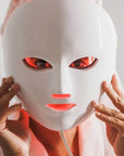 Woman holding Evara Beauty LumiGlow LED face mask